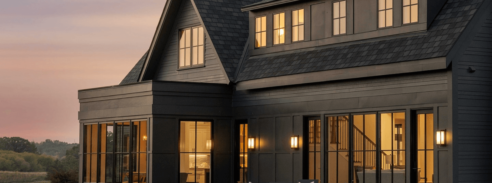 A dark gray house with new black windows at dusk.
